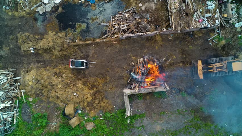 Aerial view looking down at a large fire being contained by heavy equipment and people on a construction site.