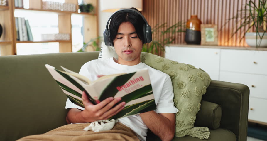Man, student and reading book in home with headphones, learning and listen to music in living room. Person, literature and research for sustainability, streaming and education with audio at apartment