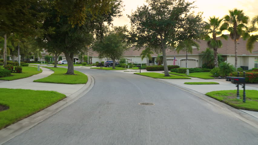 POV car driving on town street in USA. Suburban American street between private houses in Florida residential area.