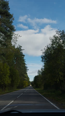 Hyper lapse from a car on a country road in clear sunny weather, forest and fields on both sides
