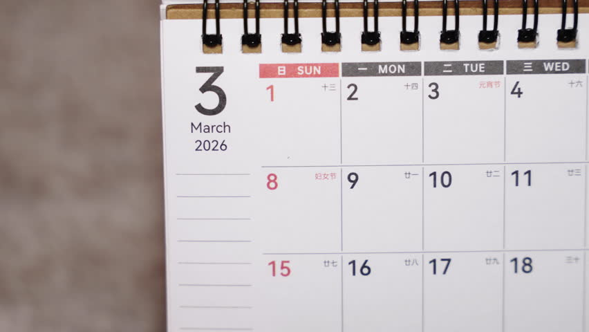 Close-up of March 2026 calendar page with pen pointing at chosen date, organization and time planning concept.