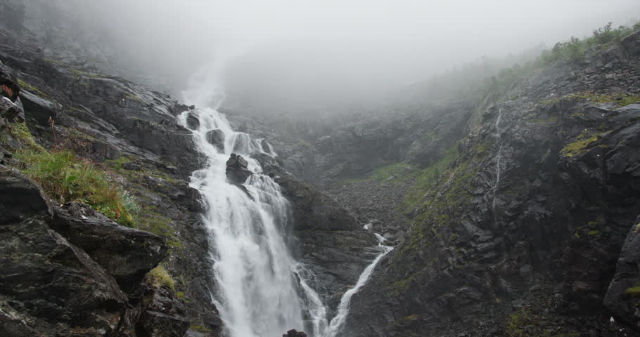 Moody norwegian waterfall cascading down a foggy mountain
