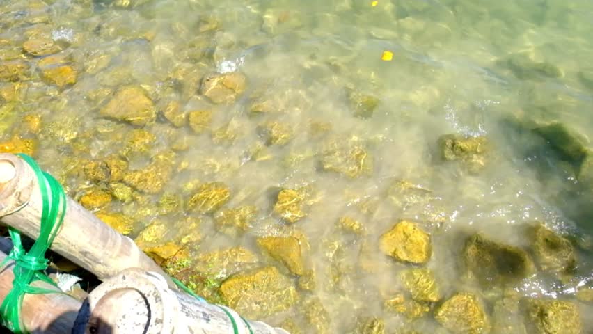 Tranquil shallow water wave with visible rocks beneath the surface on a sunny day
