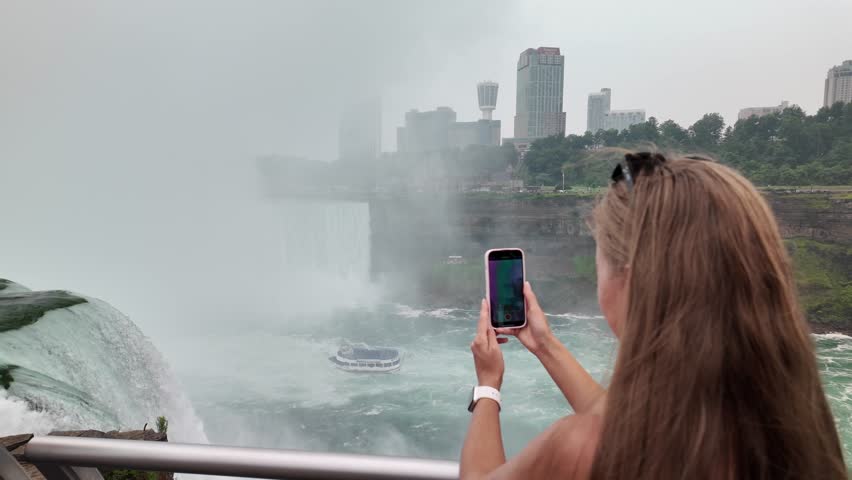 Woman tourist taking smartphone video of niagara falls