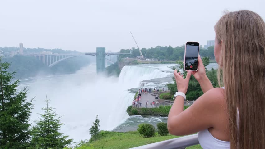 Woman taking a picture of niagara falls with her smartphone