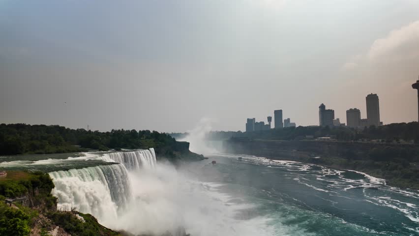 Niagara falls flowing with canadian cityscape in background