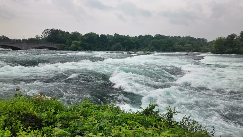 Raging niagara river whitewater rapids flowing under a bridge