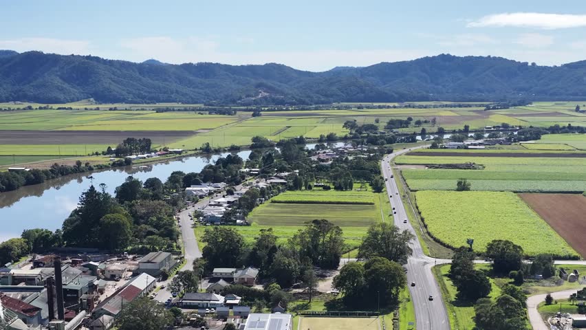 Drone footage shows an industrial factory emitting white smoke beside a winding river and farmland.