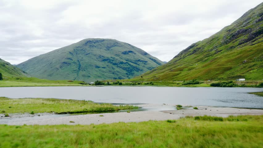 Low altitude dynamic aerial footage flying over loch achtriochtan glen coe scotland towards mountains and green hills