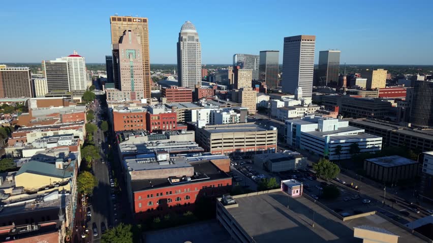 Aerial flyover of downtown Louisville, Kentucky, showcasing the city skyline, urban architecture, and clear blue sky in a scenic Midwestern city landscape