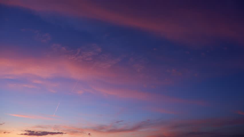 A tranquil sunrise sky timelapse video with soft pink and purple clouds drifting across a deep blue morning sky, revealing gentle cloud layers and the calm, luminous transition from night to dawn.
