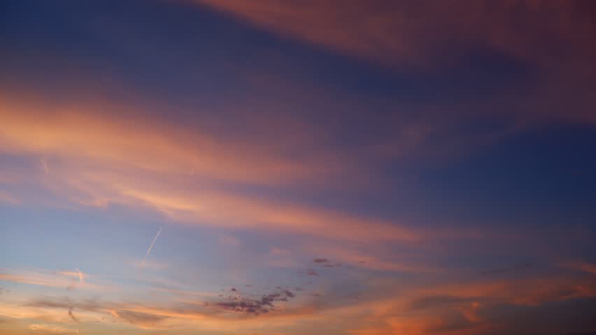 A tranquil sunrise sky timelapse video with soft pink and purple clouds drifting across a deep blue morning sky, revealing gentle cloud layers and the calm, luminous transition from night to dawn.