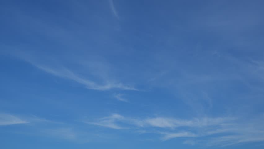 A calm blue sky timelapse video with thin, wispy clouds gently flowing across a vast clear atmosphere, emphasizing smooth cloud motion, openness, and the peaceful beauty of a serene daytime sky.
