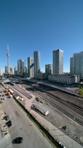 Aerial panning view of toronto skyline with cn tower, modern skyscrapers and converging railway tracks under clear blue sky