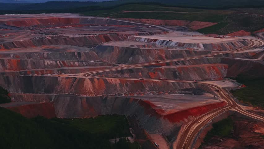 Aerial view of extensive open pit mining in scenic mountainous landscape at dusk, industry landscape in nature color.