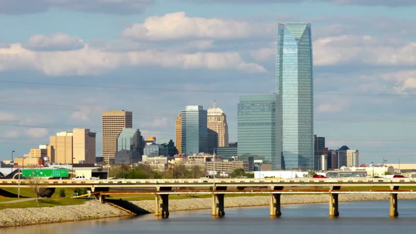 "Oklahoma City skyline with a bridge spanning the river, capturing urban architecture, waterfront, and scenic city views in daylight."