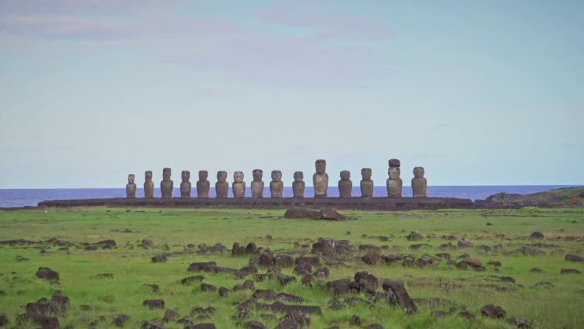 Moai statues standing in a row on Easter Island against a clear blue sky, ancient stone figures symbolizing Polynesian history.