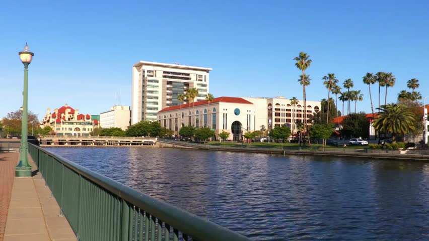 Scenic Stockton, California waterfront with modern buildings and palm trees along the marina, calm urban riverside atmosphere.