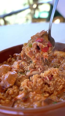 A spoon is in a bowl of food. The bowl is red