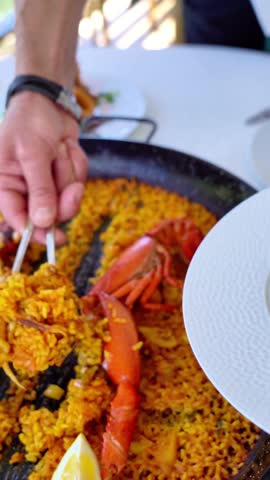 A man is serving food from a plate with a crab on it. The plate is on a table with a fork and knife