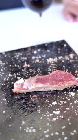 A piece of meat is being cooked on a black surface