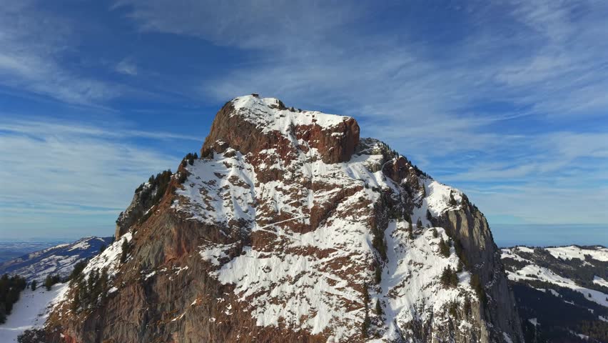 Cinematic drone footage orbiting around the rugged, snowy summit of the iconic Grosser Mythen mountain in Canton Schwyz.