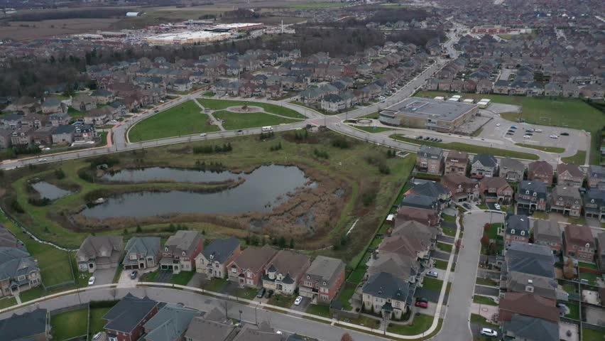 Don mills high altitude perspective of a contemporary residential subdivision featuring detached homes, a roundabout, and a central park with a pond. Toronto ontario