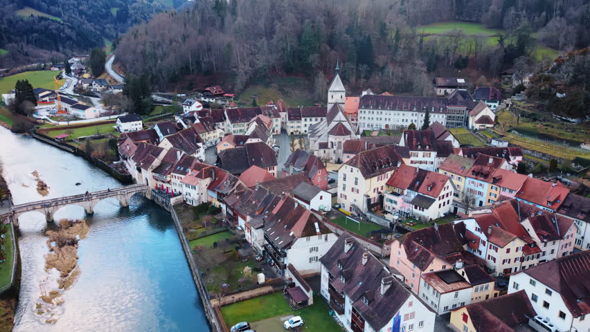 Aerial: Saint-Ursanne cityscape during the day in Clos du Doubs, canton of Jura, Switzerland, pull out drone shot