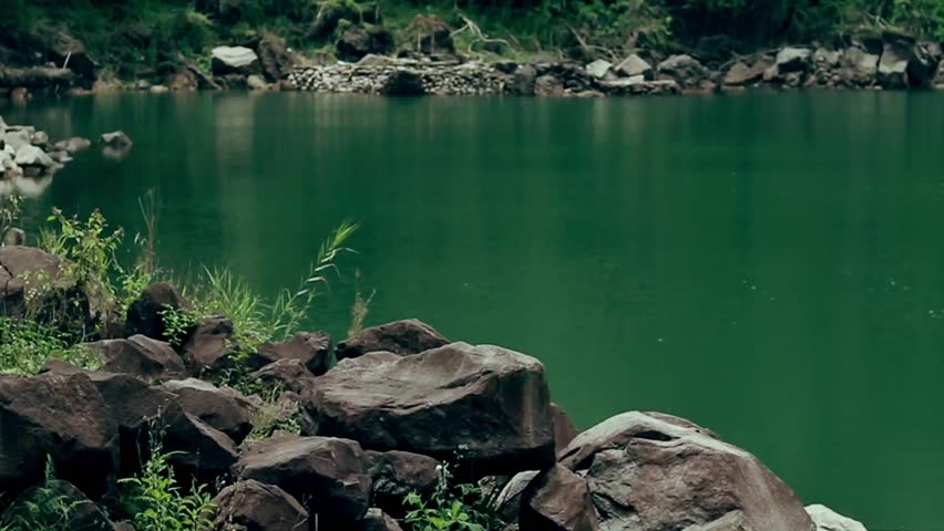 A serene lake surrounded by rocks and greenery in a peaceful setting. Balinsasayao Twin Lakes Natural Park in Sibulan, Negros Oriental, Philippines