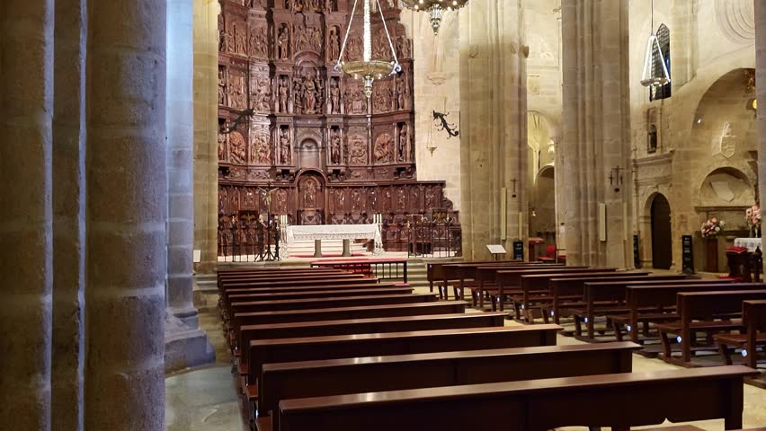 Caceres Cathedral. Panoramic view of the interior of a Gothic temple. Stone columns, arches, and ceilings. Main altarpiece carved in wood. Spanish religious art.