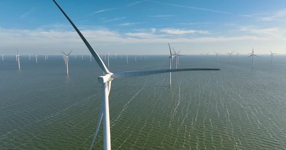 Aerial view of an offshore wind farm in the sea under a clear sky. Drone shot of wind turbines generating renewable energy in the ocean. Concept of clean sustainable power, green technology, and future industrial ecology.