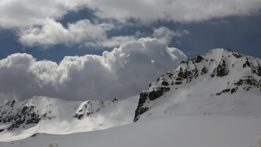 Time lapse view of snowy New Zealand mountain climate with fast moving clouds and icy peaks. Accelerated clouds reveal harsh cold weather, frozen slopes, and dramatic alpine atmosphere.
