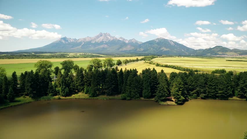 Flying over lake towards majestic high tatras mountains on sunny summer day aerial view of slovakia nature