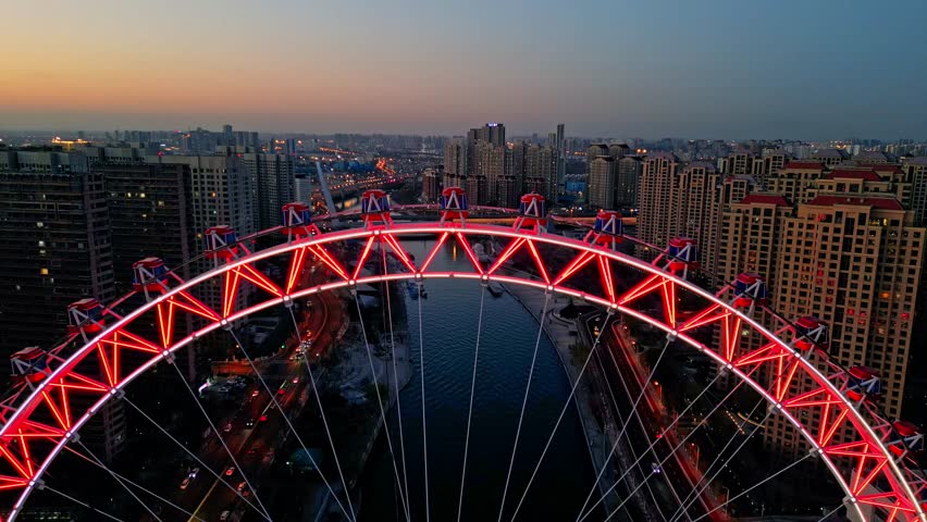 Aerial view of the red-lit Tianjin Eye Ferris wheel over the river contrasting with the backdrop of buildings, Tianjin, Tianjin, China.