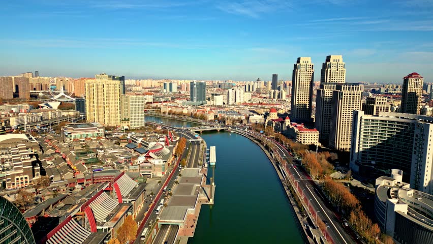 Aerial view of the winding Hai River cutting through the city, framed by skyscrapers and the Tianjin Eye, showcasing urban development, Tianjin, Tianjin, China.