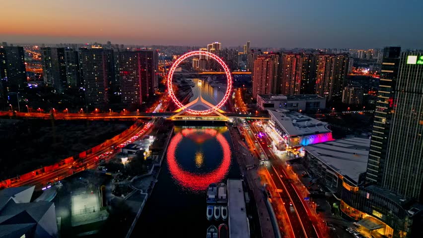 Aerial view of the neon-lit Tianjin Eye Ferris wheel reflected in the river, contrasting with the surrounding buildings, Tianjin, Tianjin, China.