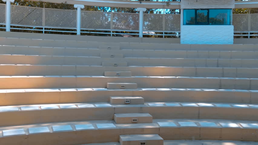Stone seats for spectators, arranged in a semicircle around the stage like an ancient amphitheater, are located on the grounds of a modern hotel. Shot in motion