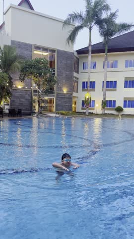 An Asian boy enjoying his vacation by swimming on the swimming pool