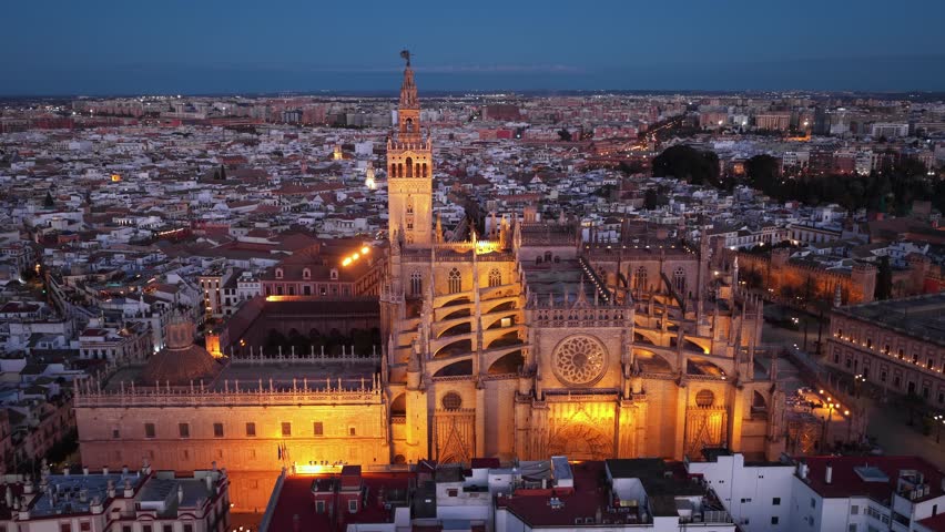 aerial orbiting shot of Seville gothic cathedral with famous Giralda bell tower. Travel in Seville, Spain.