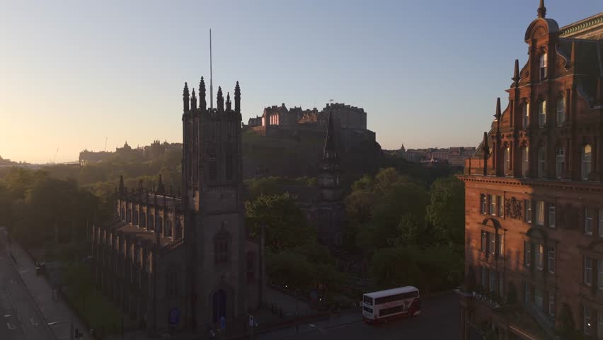 Aerial view of Edinburgh Castle perched atop a rugged hill, contrasting with the surrounding green trees and city buildings, Edinburgh, Scotland, United Kingdom.