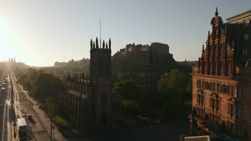 Aerial view of the historic Edinburgh Castle perched atop a hill, contrasting with the church and lush greenery below, Edinburgh, Scotland, United Kingdom.
