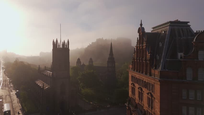 Aerial view of Edinburgh Castle shrouded in mist behind the church, the soft light casting shadows, Edinburgh, Scotland, United Kingdom.