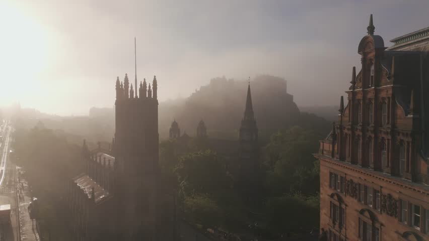 Aerial view of a majestic church with a tall spire and Edinburgh Castle in the misty background under a soft, diffused light, Edinburgh, Scotland, United Kingdom.