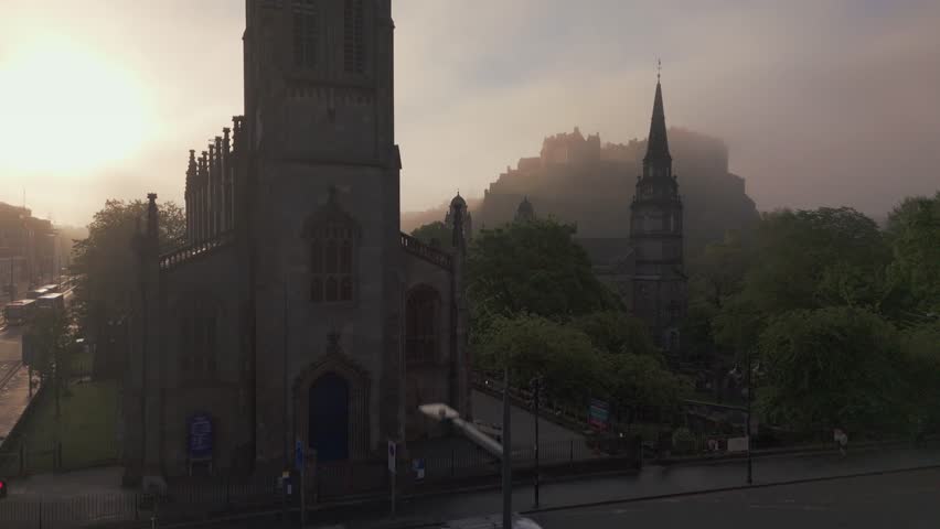 Aerial view of Edinburgh Castle and the city shrouded in a thick fog, creating a mystical atmosphere with visible steeples, Edinburgh, United Kingdom.