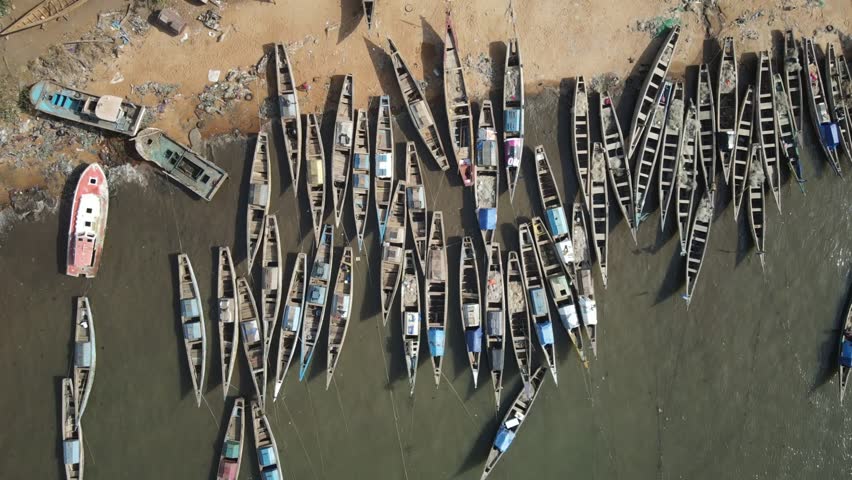 Aerial view of a roundabout with lush green trees surrounded by a coastal road near the beach, Freetown, Sierra Leone.