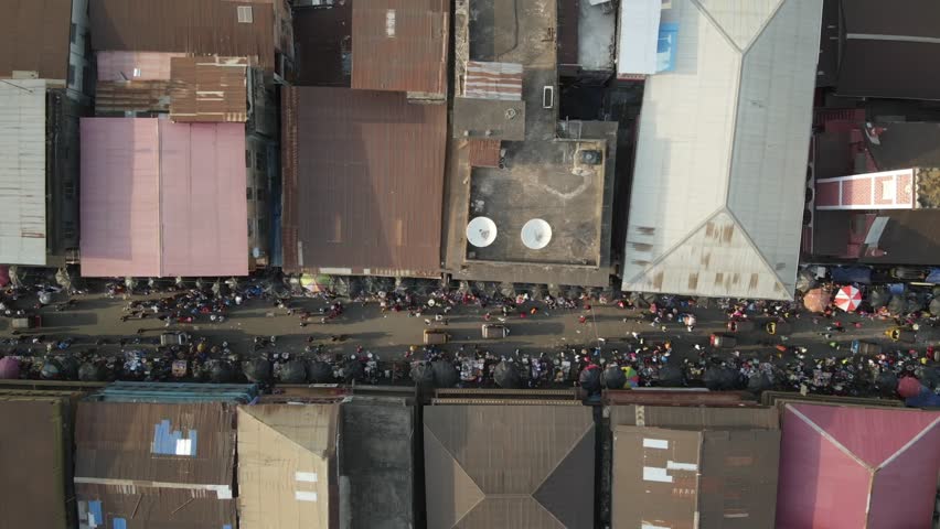 Aerial view of Sanni Abacha Street bustling with vibrant activity, colorful umbrellas, and dense crowds nestled between buildings, Freetown, Western Area, Sierra Leone.
