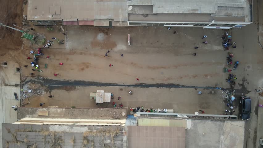 Aerial view of people walking and trading on a dusty street, contrasting with the buildings and vehicles, Conakry, Conakry, Guinea.