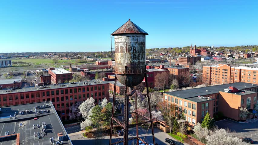 Aerially closing the distance to a water tower that stands strong amongst a historic district