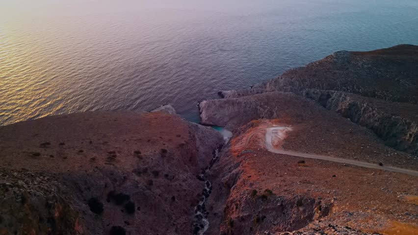 Aerial view of the rugged coastline meeting the tranquil sea, displaying contrasting textures and tones, Seitan Limania, Akrotiri, Greece.