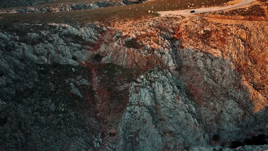 Aerial view of the rugged Seitan Limania cliffs meeting the dark blue sea, creating a striking contrast of textures and tones, Akrotiri, Chania, Greece.